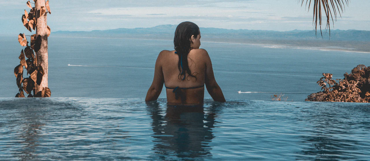 Woman relaxing in an infinity pool overlooking the ocean