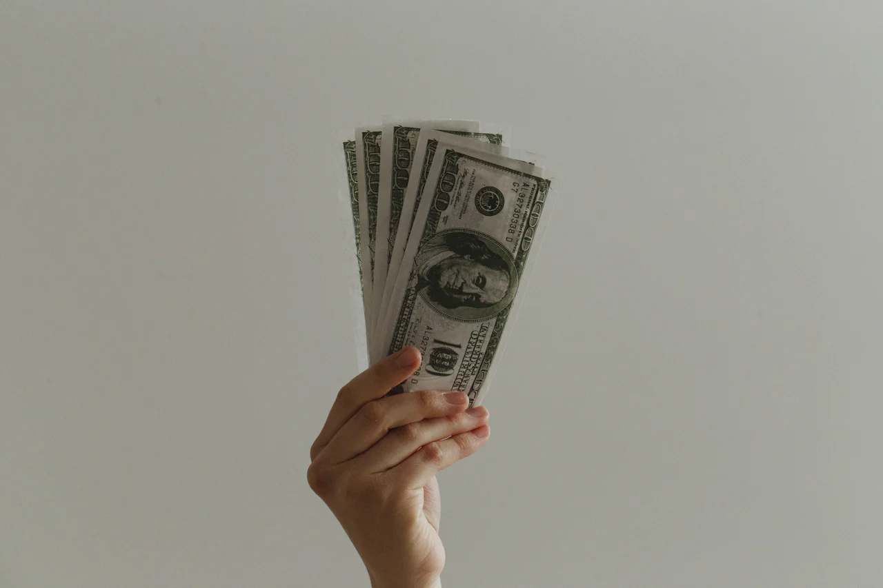 A hand holding US hundred-dollar bills